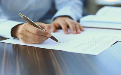 A person signing an agreement - How to Diagnose and Respond to Merchant Churn