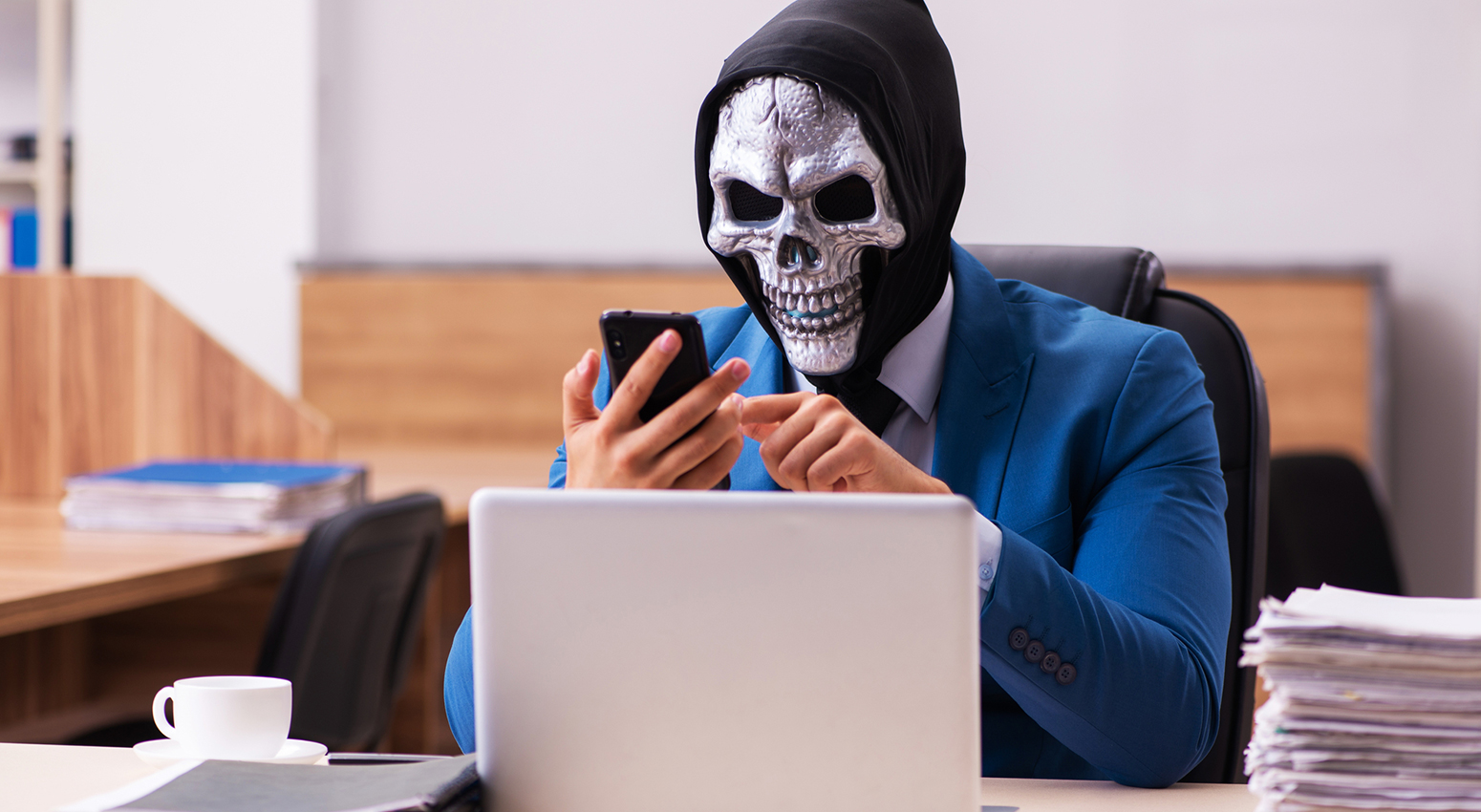 A person in a scary mask on their phone at a desk - A Guide to Un-disguising the Unauthorized Sellers of Ghost Sellerville